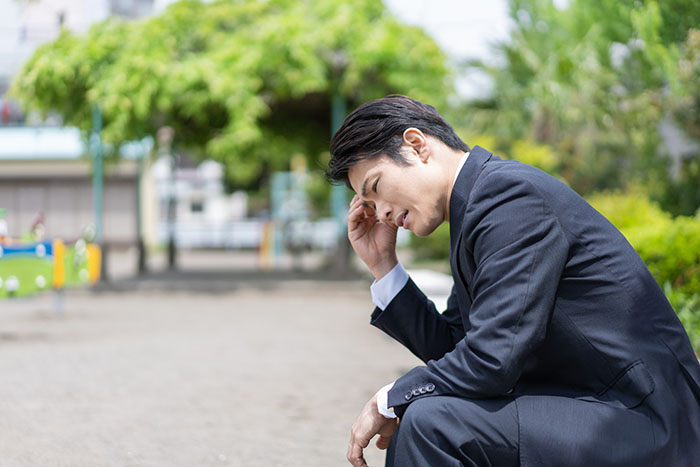 公園のベンチで悩む男性