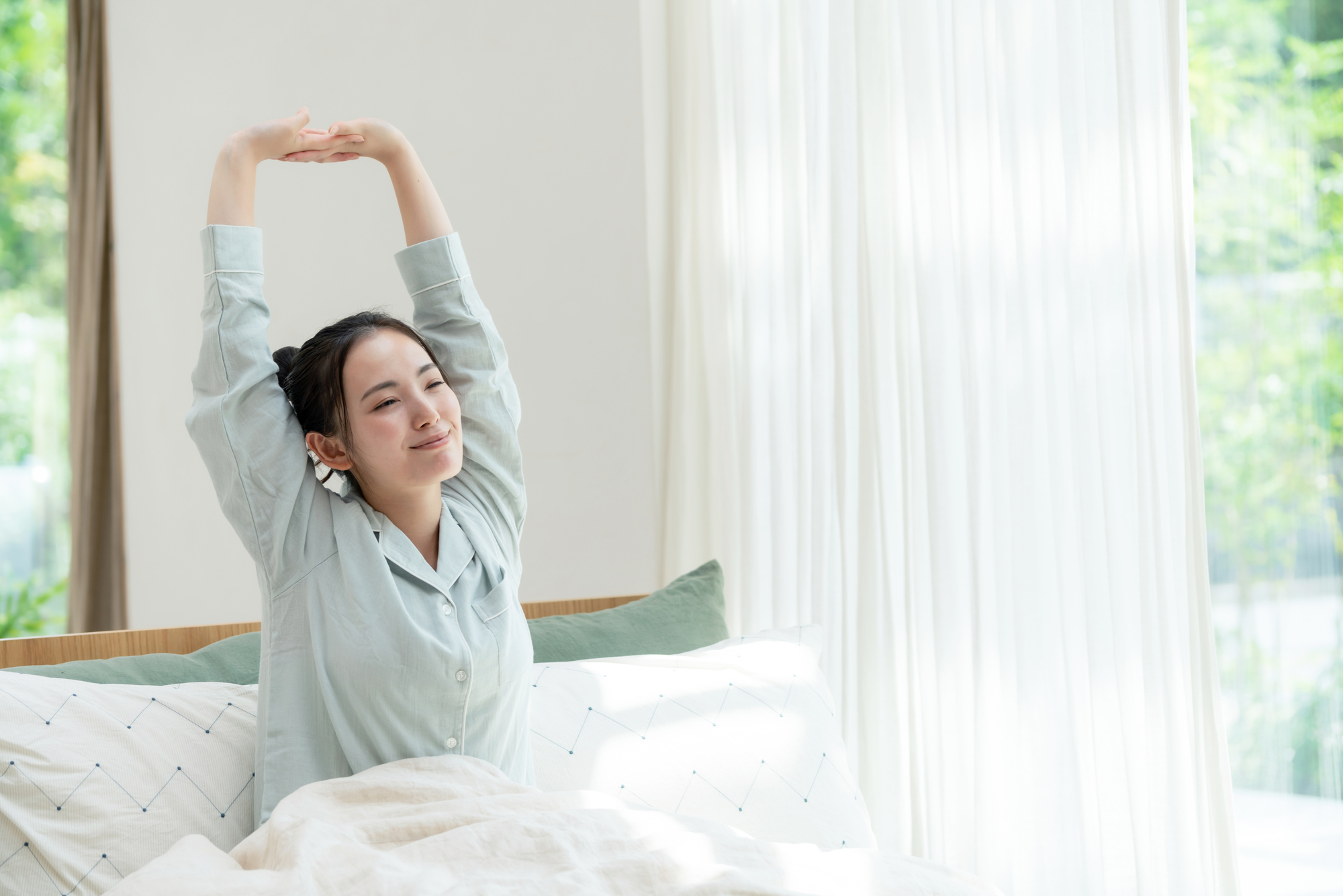 朝、体を伸ばしている起床した女性