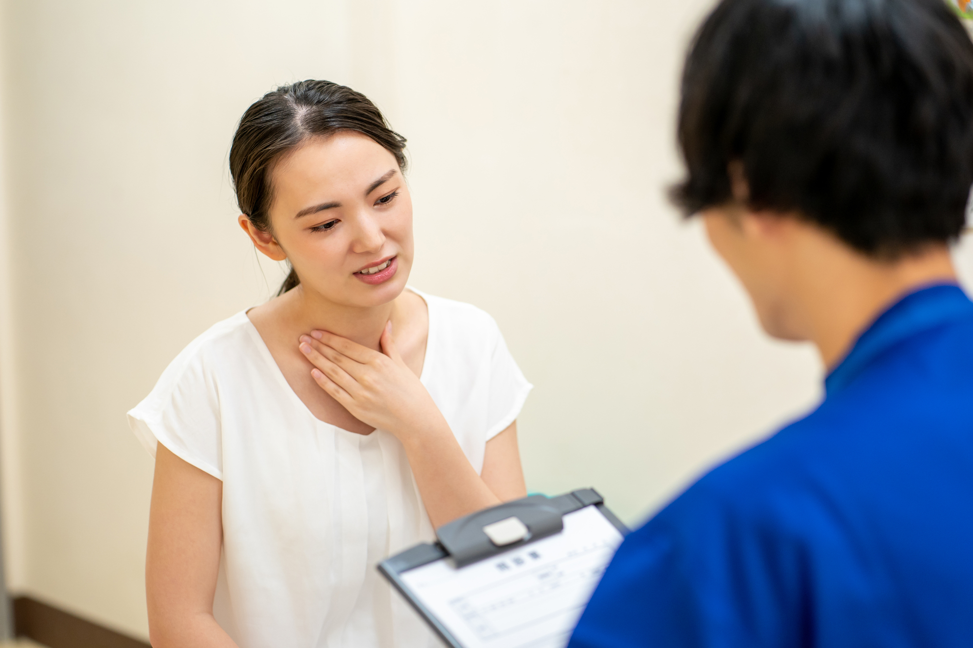 のどについて医師に相談する女性