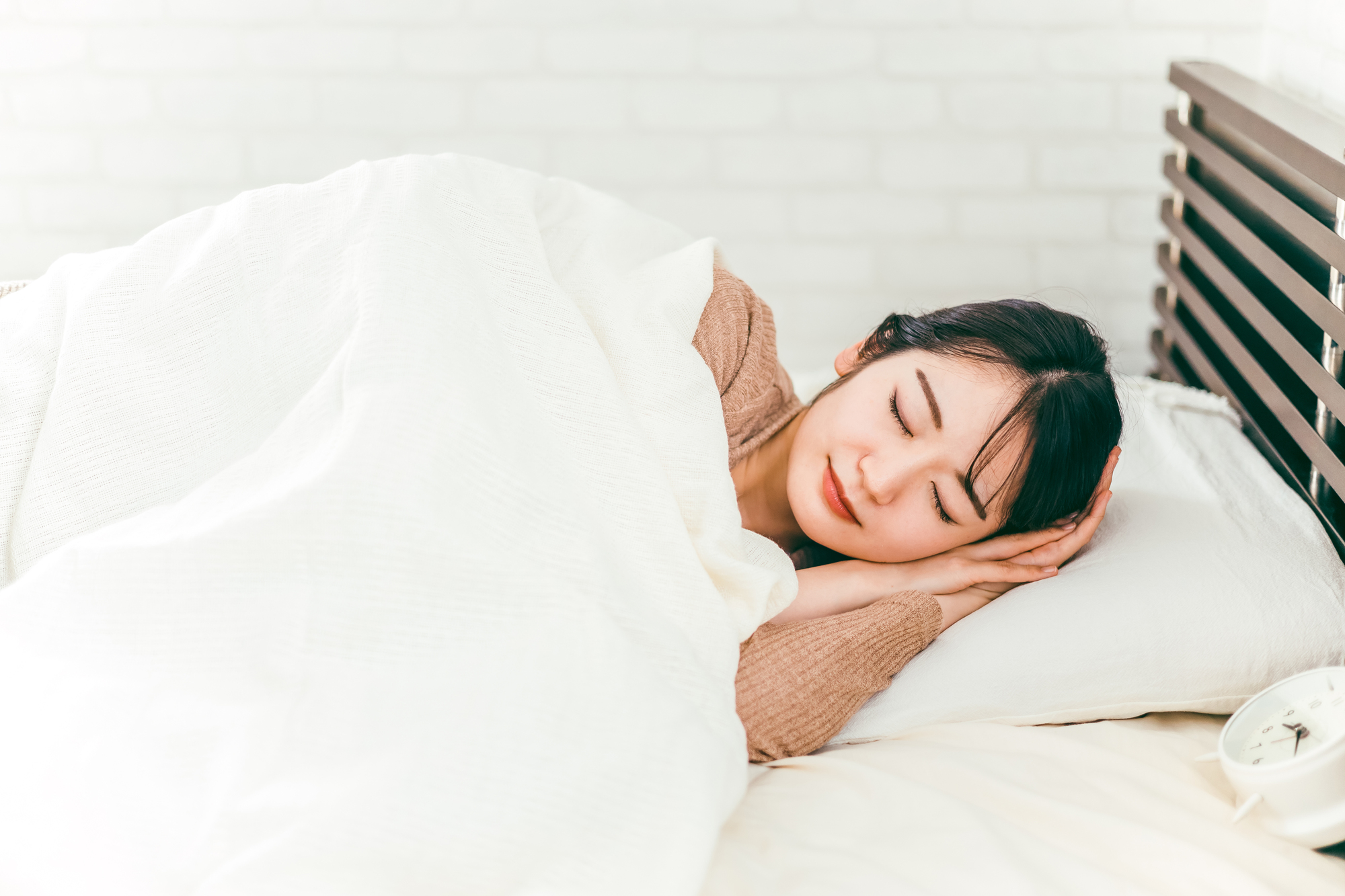 白いシーツのベッドで眠る女性