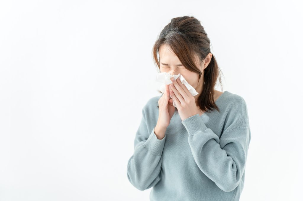 ティッシュで鼻をかんでいる女性