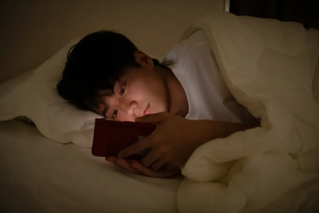暗い部屋でスマホをいじる男性