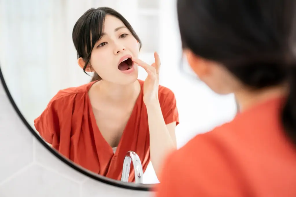 口を広げて口内を確認する女性