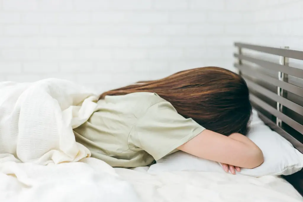 ベッドで伏せて寝ている女性